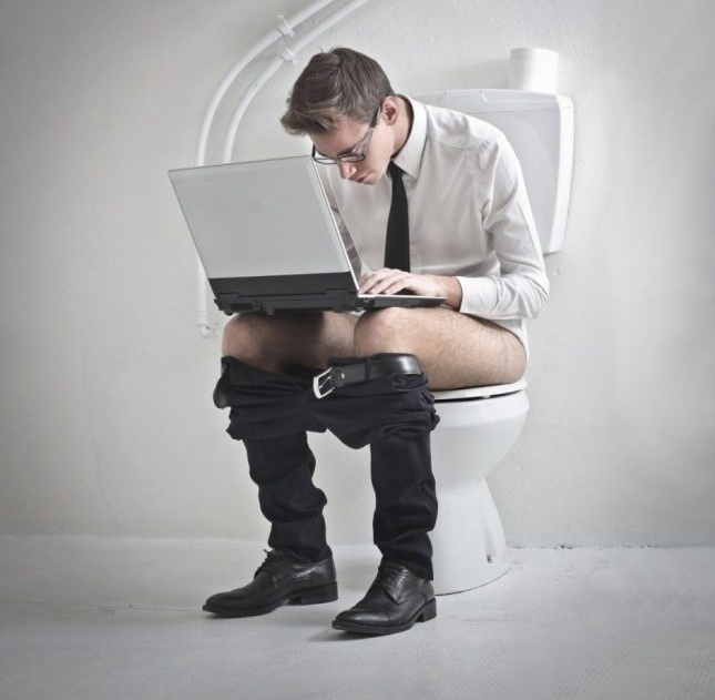 Мъж с лаптоп на тоалетната