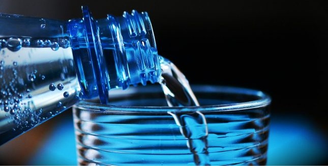 Налейте вода от бутилка в чаша